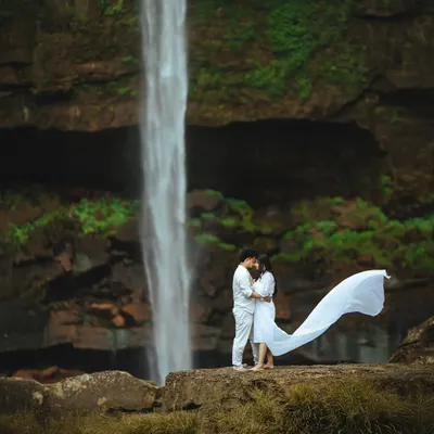 Her dress catching the wind like a sail, creating a moment of pure cinematic beauty in front of the powerful waterfall. This shot combines movement, nature, and romance for a truly breathtaking pre-wedding portrait.
