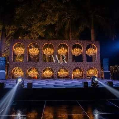 The main stage for a fairytale sangeet. I designed this custom backdrop with two tiers of arched niches, each holding a sparkling chandelier, creating a spectacular wall of light for the performances.