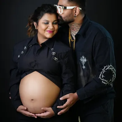 A tender moment captured in our studio. The father-to-be kisses his partner's forehead as they both gently hold the baby bump, creating a powerful image of love and connection.