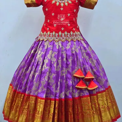 A magnificent Kanchi pattu lehenga in a classic red and purple combination. The red raw silk blouse features intricate stone and zari work, while the purple Banarasi skirt has a wide, traditional temple border.