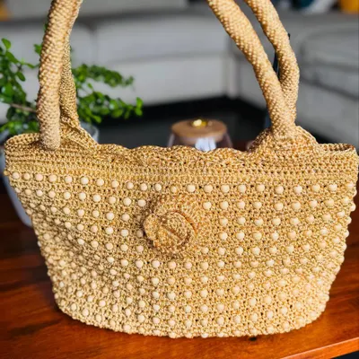 A full view of my handcrafted gold bag, intricately woven with beads for a classic look. The scalloped edge and detailed flower add a touch of timeless elegance.