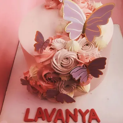 A beautiful pink cake adorned with buttercream rosettes and delicate, edible butterflies. A lovely choice for a birthday or special occasion.