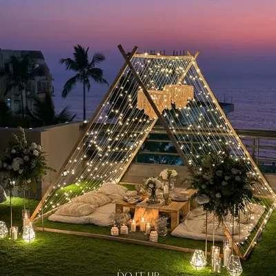 A magical evening under the stars. I designed this intimate teepee setting for a special proposal, using layers of fairy lights and soft cushions to create a space that felt like a private world, perfect for a once-in-a-lifetime moment.