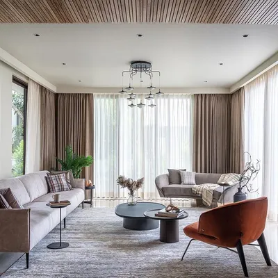 This living space is a perfect example of modern elegance, with a neutral color scheme, clean-lined furniture, and a pop of burnt orange in the armchair for warmth and personality.
