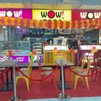 A vibrant balloon garland decoration for the grand opening of a WOW! Momo store. The red and yellow balloons match the brand's colors, creating a festive and inviting look for the new outlet.
