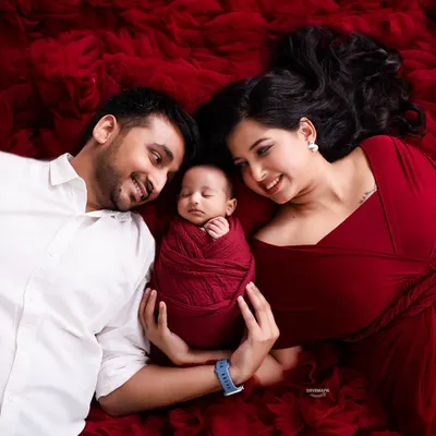 An overhead family portrait allows for a unique perspective, beautifully framing the three of you together. The rich red fabric adds a touch of elegance to this tender moment with your sleeping baby.