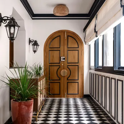 The entryway of our 'Getaway to Galle' project sets a tropical tone with its arched wooden door, checkerboard floor, and traditional lanterns. The space immediately transports you to a breezy, coastal villa.
