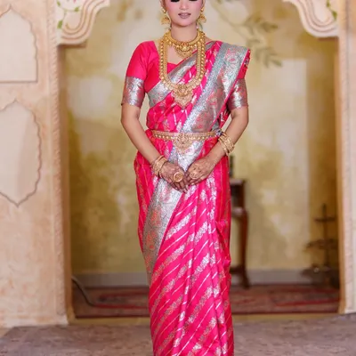 A full-length portrait of our stunning South Indian bride. The pink and silver Kanjeevaram saree is paired with classic temple jewelry and a clean, elegant makeup look.