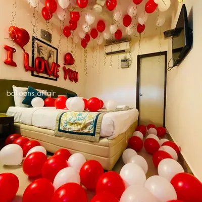 The quintessential romantic room setup. This hotel room is filled with red and white balloons on the floor and ceiling, with a bold "I LOVE YOU" message above the bed.