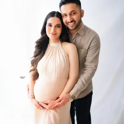 A classic and beautiful family portrait. The expecting couple looks so happy and connected in this bright, light-filled studio shot, creating a timeless memory.