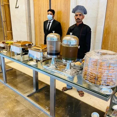 Our professional team ready to serve at a house warming ceremony at Lodha World Towers. The setup includes drink dispensers, chafing dishes for hot food, and a station for puris.