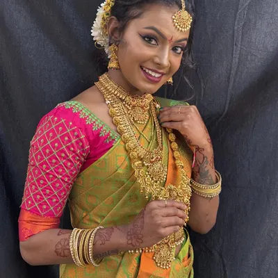 A classic South Indian bridal look featuring a radiant smile and traditional temple jewelry. We ensure the makeup complements the vibrant silk saree and enhances the bride's natural beauty.