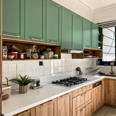 This kitchen features a beautiful two-tone design with sage green upper cabinets and natural wood lower cabinets. The open shelving provides easy access to spices and everyday items.