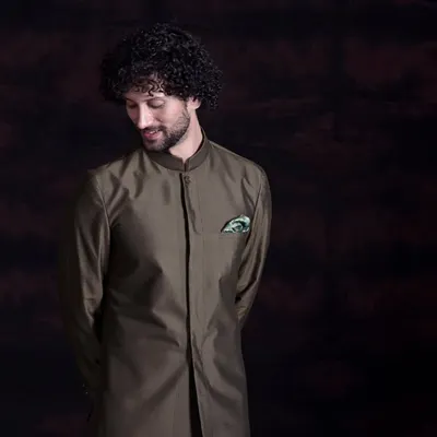 This sherwani-style kurta in a deep olive green is a statement in understated elegance. The clean, longline silhouette and mandarin collar offer a refined masculinity, proving that true luxury whispers rather than shouts.