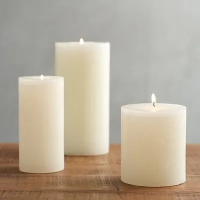 Three of my classic ivory pillar candles lit and arranged on a wooden surface. Their warm, steady flame is perfect for creating a relaxing atmosphere for a candlelight dinner or quiet evening.