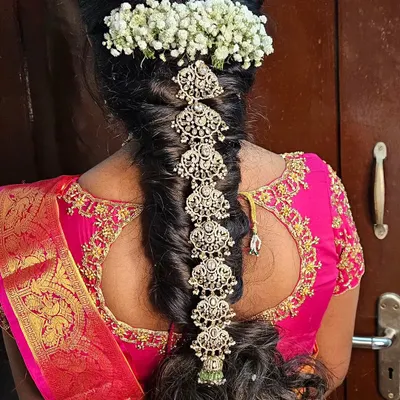 A close-up of a traditional South Indian bridal hairstyle. This beautiful braid is adorned with silver jada billai and fresh jasmine flowers, creating a classic and fragrant look.