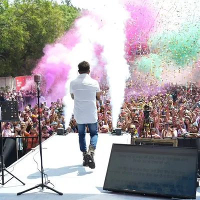 The legendary Sukhwinder Singh on stage, surrounded by a cloud of pink and green colors during the GSC Ranga Rang Holi festival. We combine live music with dynamic special effects for an unforgettable celebration.