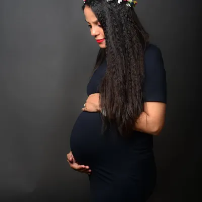 A serene and beautiful solo maternity portrait. The flower crown adds a soft, natural touch to this classic profile shot celebrating motherhood.
