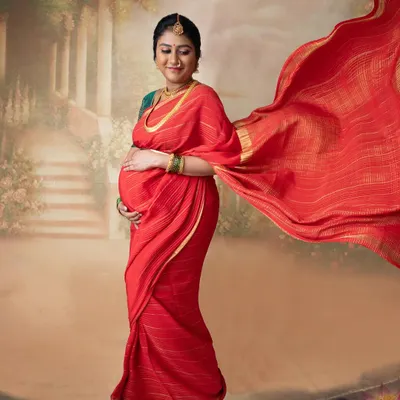 The elegance of a flowing red saree against a painted backdrop. This is the starting point for creating a timeless, painting-style portrait that feels both classic and personal.