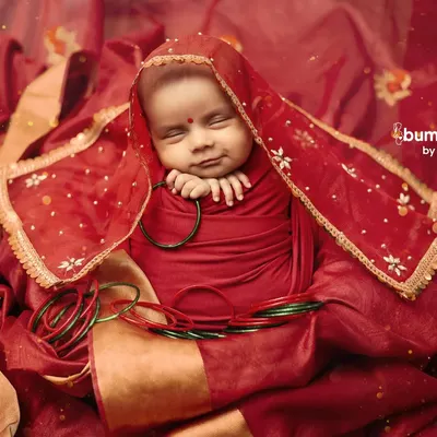 A tiny, peaceful smile on our little devi. This Navratri newborn portrait, with the baby wrapped in red and gold, is a picture of pure serenity.