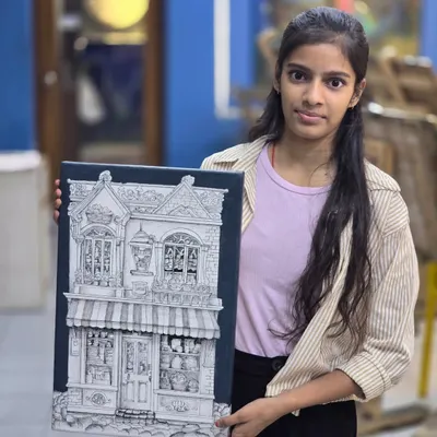 A proud student holds her incredibly detailed micron pen drawing of a storefront, a piece that required immense patience and skill.