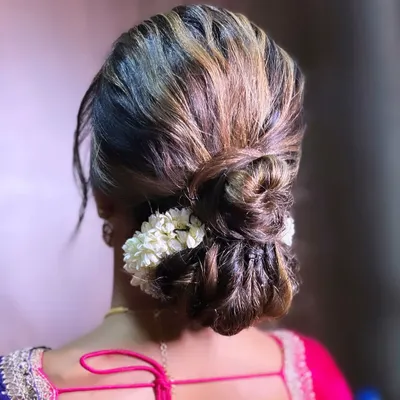 A modern classic, this textured low bun is interwoven with strands of hair and adorned with a simple gajra of jasmine flowers. It's an elegant choice for any occasion, from a wedding to a formal party.