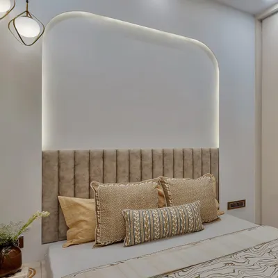 This bedroom showcases a beautiful play of textures. The fluted velvet headboard, patterned bedding, and smooth, curved wall niche with integrated lighting create a rich and tactile experience.
