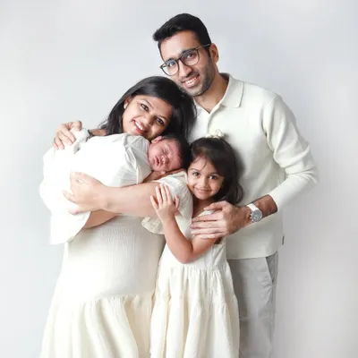 A perfect frame of four. This portrait captures the joy of a growing family, with a new baby brother being welcomed with so much love by his parents and big sister.