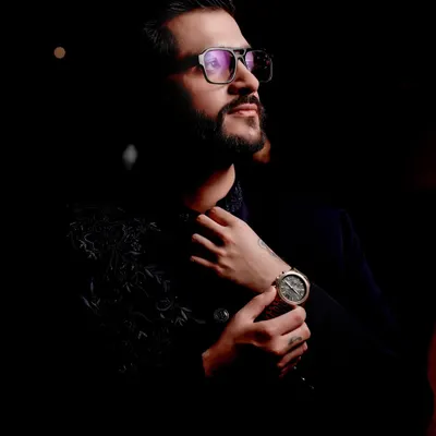 A moody and stylish portrait of the groom, his sharp attire and confident look captured in dramatic lighting.