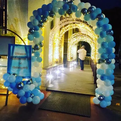 A simple blue and white balloon arch creating an inviting entrance for Muhammed Ali's first birthday party. The arch leads guests through a beautifully lit walkway.
