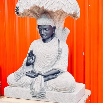 An intricately carved Buddha statue sitting under a stone Bodhi tree. This is a high-quality statement piece for any garden.
