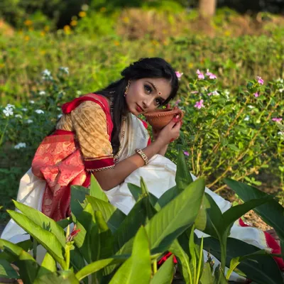 A beautiful portrait from a Bengali-themed shoot in a garden. The soft light and natural surroundings perfectly complement her traditional attire, creating a look straight out of a movie.