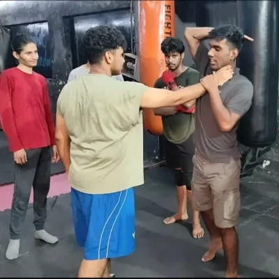 A coach demonstrates a practical self-defense technique, showing a student how to break free from a chokehold. These skills are invaluable for personal safety.