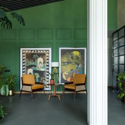 This seating nook in a sales lounge for a senior living community uses a rich green accent wall and warm, comfortable armchairs. The space is designed to feel more like a welcoming living room than a commercial office, fostering a sense of ease and tranquility.