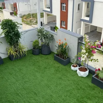 A wide angle view of a completed terrace makeover, showcasing a spacious artificial lawn surrounded by curated plants. This demonstrates how we can turn an empty rooftop into a functional and beautiful extension of your living space.