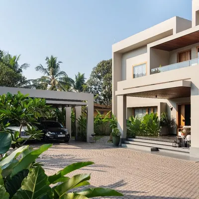 The exterior of the Faizal Residence features a modern, block-like structure softened by lush landscaping. The design provides a grand sense of arrival while maintaining a connection to the tropical Kerala environment.