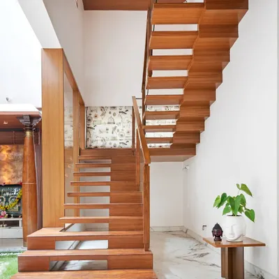 This floating staircase in the Twin Courtyard House is a work of art. The teak wood steps appear to be suspended, creating a sense of lightness, while the wide lower steps provide a casual seating spot near the pooja room.