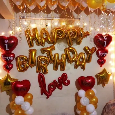 A classic romantic birthday surprise decoration. This wall setup features gold "Happy Birthday" foil letters, red heart-shaped balloons, and warm fairy lights to create a cozy and loving atmosphere.