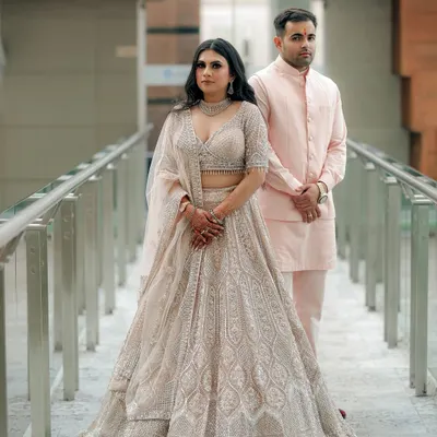 A formal portrait from an engagement ceremony. The couple's coordinated pastel outfits and the modern architectural background of the venue create a sophisticated and elegant look.