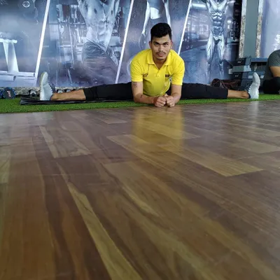 Holding a front split on the gym floor. This level of flexibility is achievable with dedicated practice and proper guidance.