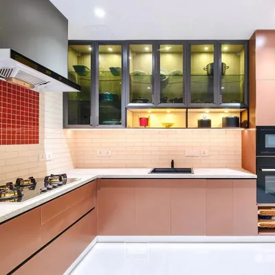 A sophisticated kitchen featuring rose-gold colored cabinets, a red mosaic tile backsplash, and glass-fronted upper cabinets with internal lighting. The built-in oven and microwave unit ensures a seamless look.