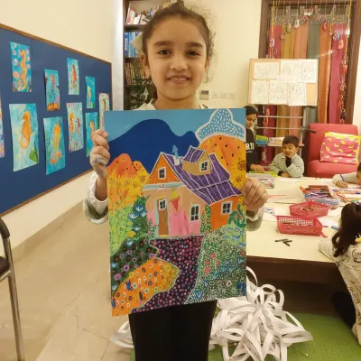 Happiness is a finished work of art. This 8-year-old student proudly displays her colorful house painting, done with acrylics on paper.