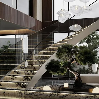 A luxurious double-height foyer featuring a curved staircase with marble steps and integrated lighting. A bonsai tree and an indoor water feature at the base create a serene and grand entrance.