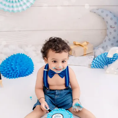 A happy birthday boy enjoying his very own blue cake. The pure delight on his face is what makes cake smash photography so special.