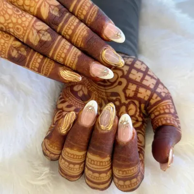 A stunning example of bridal nails designed to complement traditional henna. This set features a clean base with intricate gold detailing and a touch of sparkle, creating a look of pure elegance.