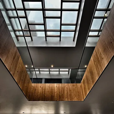 Looking up through a central atrium at the Drishya project. The gridded skylight and wood-clad walls create a powerful architectural statement while drawing natural light deep into the home.