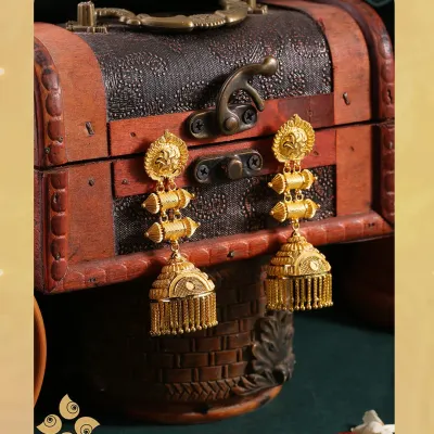 A pair of stunning three-tiered jhumka earrings in pure gold, showcasing traditional design with beautiful fringe detailing. A must-have for any festive collection.