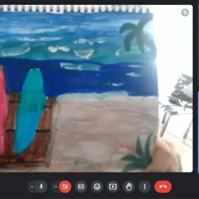 A student proudly shows his finished beach scene painting during our online class. I provide step-by-step guidance to help them create beautiful art from home.