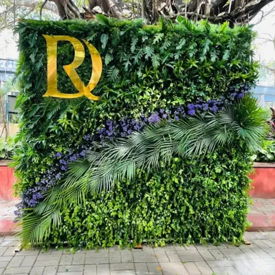 This photo booth backdrop is a dense wall of natural greenery, featuring a diagonal arrangement of purple flowers and palm leaves. I added a custom gold monogram to personalize it for the event.