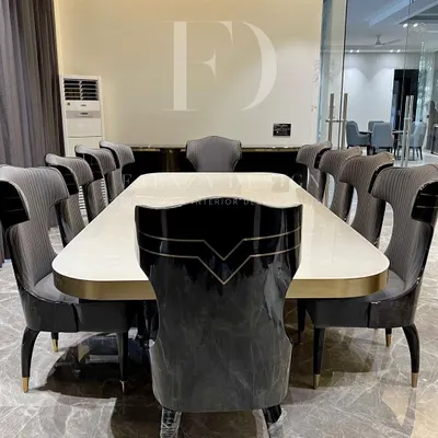 An opulent 10-seater dining set. The table features a lustrous white onyx top with a brass-trimmed base, surrounded by high-back chairs with unique cut-out details and dual-fabric upholstery.